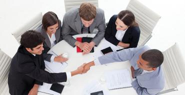 Grupo de personas cerrando un negocio en mesa redonda