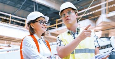 Mujer y hombre con casco de construcción blanco conversando