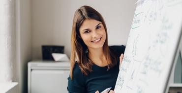 Mujer escribiendo una estrategia de mercadeo en un tablero