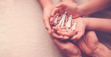 Manos unidas con un  un recorte en papel de una familia