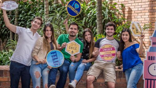 Grupo de estudiantes con carteles de diferentes países y mensajes positivos