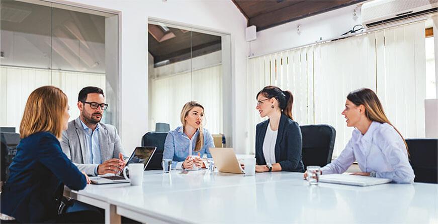 Grupo de personas en reunión revisando sus computadores