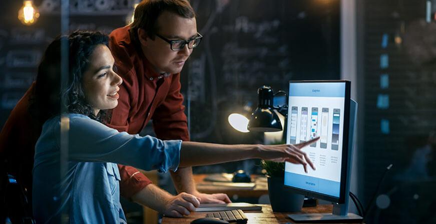 Mujer y hombre mirando la estructura de una aplicación en la pantalla de un computador