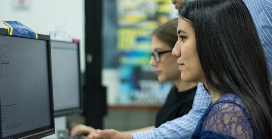 Estudiantes frente a computador revisando balances y cifras