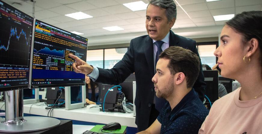 Profesor y estudiantes de finanzas revisando cifras y comportamiento de la bolsa